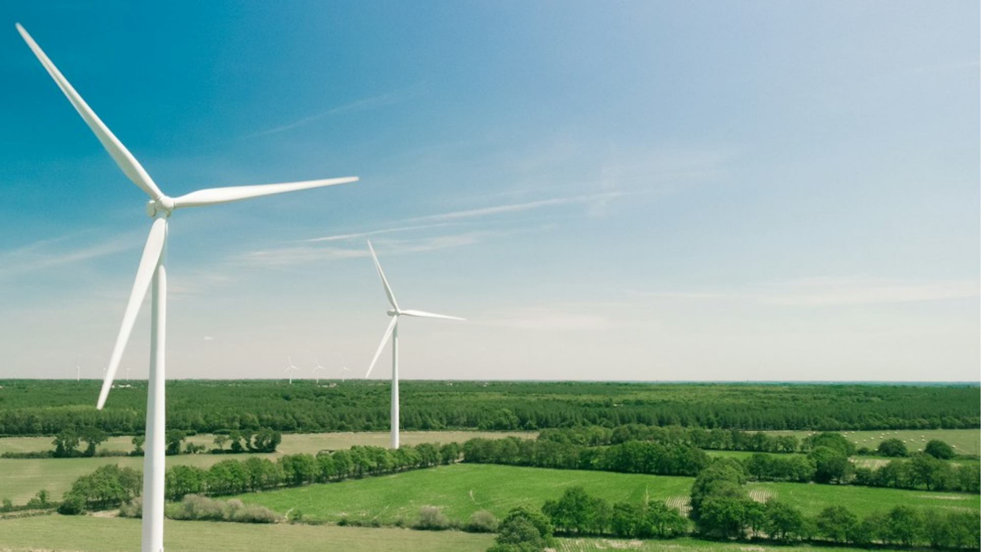 Image of a wind farm above green farmland.